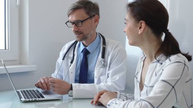 Parlak, modern bir muayenehanede muayene sırasında test sonuçlarını açıklamak için dijital tablet kullanan kadın doktor. Tıp konsepti.