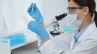 Laboratuvar analizi sırasında cam şişeye kimyasal solüsyon yerleştiren koruyucu giysi araştırmacısı, beyaz arka plan. Tıp, sağlık ve bilim konsepti