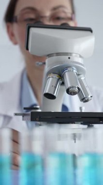 Kadın laboratuar bilimcisi mikroskop kayışını dikkatlice yerleştiriyor. Laboratuvarda araştırma hassasiyetini gösteriyor. Tıp, sağlık ve bilim konsepti.