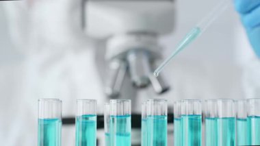 Mavi koruyucu eldivenler giyen bilimsel araştırmacıların ellerini kapatın. Tıbbi araştırma yaparken sıvıyı test tüplerine dikkatlice yerleştirin. Tıp ve bilim konsepti.