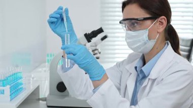 Laboratuvar analizi sırasında cam şişeye kimyasal solüsyon yerleştiren koruyucu giysi araştırmacısı, beyaz arka plan. Tıp, sağlık ve bilim konsepti