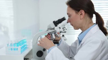 Laboratuvar önlüğü ve koruyucu gözlüklü kadın bilim adamı modern bir laboratuvarda mikroskop altında test örnekleri inceliyor. Tıp, sağlık ve bilim konsepti