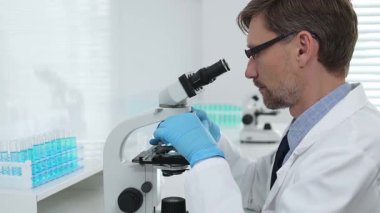 Gelişmiş laboratuvar araştırmaları sırasında mikroskopla biyolojik örnekleri inceleyen odaklanmış bir tıp bilimcisi. Tıp, sağlık ve bilim konsepti