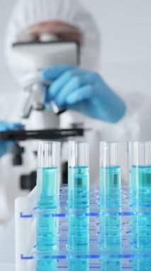 Koruyucu ekipman ve mavi eldiven giyen bilim araştırmacısı veya virolog tıbbi laboratuvar araştırması sırasında mikroskop lenslerini ayarlıyor. Tıp, sağlık ve bilim konsepti.