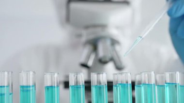 Mavi koruyucu eldivenler giyen bilimsel araştırmacıların ellerini kapatın. Tıbbi araştırma yaparken sıvıyı test tüplerine dikkatlice yerleştirin. Tıp ve bilim konsepti.