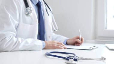 Mavi steteskop, klinikteki panoda doktor adamın profesyonel yazısının yanında duruyor. Tıp ve sağlık hizmetleri kavramı.