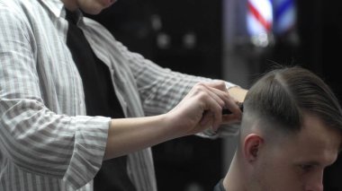 Profesyonel berber saç kesiminden önce müşteri saçını tarıyor, berber dükkanında stil yapmaya hazırlanıyor, erkekler için modern saç stili yaratıyor, güzellik salonu hizmeti veriyor.