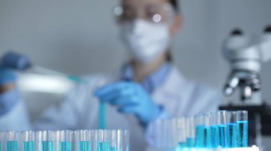 Laboratuvar tüpleri odaklandı, yakın görüş. Kadın araştırmacı, arka planda bir mikro pipet kullanıyor. Tıp ve Bilim.