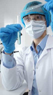 Bilimadamları laboratuvar tıbbi araştırma çalışmaları sırasında koruyucu giysi giyip tüpü hassas pipetle test etmek için kimyasal sıvı eklediler. Tıp, sağlık ve bilim konsepti