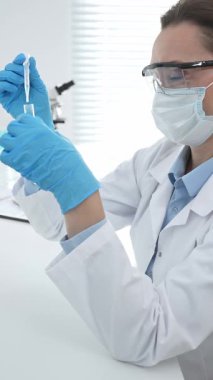 Laboratuvar analizi sırasında cam şişeye kimyasal solüsyon yerleştiren koruyucu giysi araştırmacısı, beyaz arka plan. Tıp, sağlık ve bilim konsepti