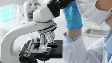 Mikroskop merceklerini inceleyen mavi koruyucu giysiler giyen, detaylı tıbbi laboratuvar araştırmaları yapan bilim adamlarına yaklaş. Tıp, sağlık ve bilim konsepti.