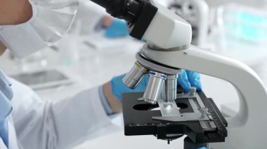 Mikroskop merceklerini inceleyen mavi koruyucu giysiler giyen, detaylı tıbbi laboratuvar araştırmaları yapan bilim adamlarına yaklaş. Tıp, sağlık ve bilim konsepti.