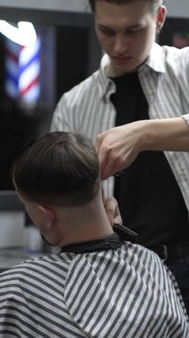 Profesyonel berber müşterilerin saçlarını elektrikli makasla dikkatlice buduyor, modern bir berber dükkanında şık ve kusursuz bir saç kesimi sağlıyor..