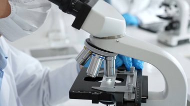 Mikroskop merceklerini inceleyen, detaylı tıbbi laboratuvar araştırmaları yapan mavi eldivenli eldiveni kapatın. Tıp, sağlık ve bilim konsepti.