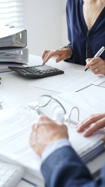 Finansal belgeleri analiz eden iş adamları, modern işyerindeki verileri parlak, profesyonel çevreyle işbirliği içinde hesaplıyorlar. İş dünyasında denetim ve vergi teması