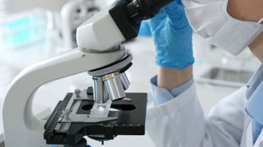 Mikroskop merceklerini inceleyen, detaylı tıbbi laboratuvar araştırmaları yapan mavi eldivenli eldiveni kapatın. Tıp, sağlık ve bilim konsepti.