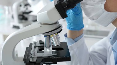 Mikroskop merceklerini inceleyen, detaylı tıbbi laboratuvar araştırmaları yapan mavi eldivenli eldiveni kapatın. Tıp, sağlık ve bilim konsepti.