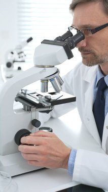 Gelişmiş laboratuvar araştırmaları sırasında mikroskopla biyolojik örnekleri inceleyen odaklanmış bir tıp bilimcisi. Tıp, sağlık ve bilim konsepti