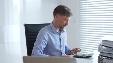 Bir ofis ortamında mali raporları incelerken, faturaları hesaplayan ve yerli faturaları yöneten olgun muhasebecilere odaklanmış. İş dünyasında denetim ve vergi teması