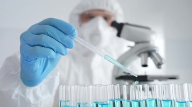 Koruyucu ekipman giyen bilimsel araştırmacıları kapatın, tıbbi araştırma yaparken dikkatlice test tüplerine sıvı pompalayın. Tıp ve bilim konsepti.