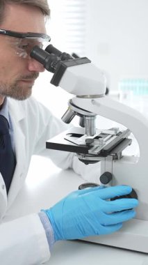 Mavi eldiven giyen tıp bilimcisi mikroskop kullanarak modern laboratuvarda bilimsel araştırma yapıyor. Tıp, sağlık ve bilim konsepti.