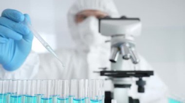 Koruyucu ekipman giyen bilimsel araştırmacıları kapatın, tıbbi araştırma yaparken dikkatlice test tüplerine sıvı pompalayın. Tıp ve bilim konsepti.