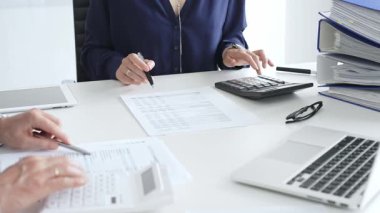 İş adamları mali belgeleri büyüteç ve hesap makinesiyle inceliyor, verileri analiz ediyor ve ofiste raporlar hazırlıyorlar. İş dünyasında denetim ve vergi teması