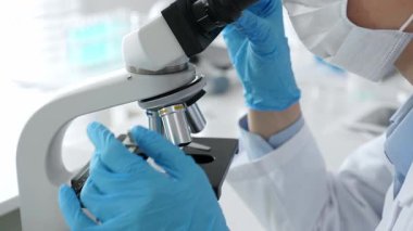 Mikroskop merceklerini inceleyen mavi koruyucu giysiler giyen, detaylı tıbbi laboratuvar araştırmaları yapan bilim adamlarına yaklaş. Tıp, sağlık ve bilim konsepti.