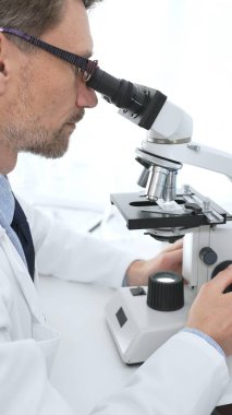 Tıp bilimadamı gözlük takıyor mikroskop kullanarak modern laboratuvarda bilimsel araştırmalar yapıyor. Tıp, sağlık ve bilim konsepti.