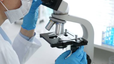 Mikroskop merceklerini inceleyen, detaylı tıbbi laboratuvar araştırmaları yapan mavi eldivenli eldiveni kapatın. Tıp, sağlık ve bilim konsepti.