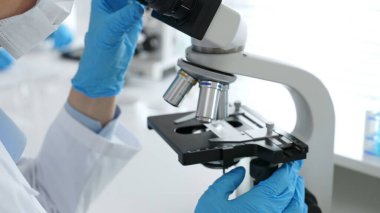 Mikroskop merceklerini inceleyen, detaylı tıbbi laboratuvar araştırmaları yapan mavi eldivenli eldiveni kapatın. Tıp, sağlık ve bilim konsepti.