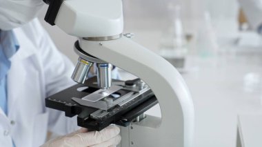 Bilim adamının beyaz eldivenli elleri parlak bir laboratuvarda mikroskobu ayarlıyor, kesinliği vurguluyor ve bilimsel araştırmalara odaklanıyor. Tıp, sağlık ve bilim konsepti.