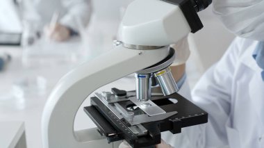 Bilim adamının beyaz eldivenli elleri parlak bir laboratuvarda mikroskobu ayarlıyor, kesinliği vurguluyor ve bilimsel araştırmalara odaklanıyor. Tıp, sağlık ve bilim konsepti.