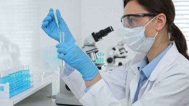 Laboratuvar analizi sırasında cam şişeye kimyasal solüsyon yerleştiren koruyucu giysi araştırmacısı, beyaz arka plan. Tıp, sağlık ve bilim konsepti