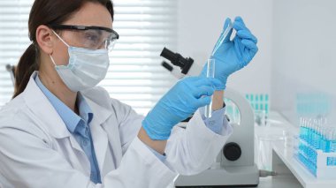 Laboratuvar analizi sırasında cam şişeye kimyasal solüsyon yerleştiren koruyucu giysi araştırmacısı, beyaz arka plan. Tıp, sağlık ve bilim konsepti