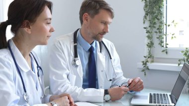 İki doktor bir dizüstü bilgisayardaki tıbbi çizelgeleri dikkatle inceliyor, bir hastane veya klinikte hastanın tıbbi geçmişini tartışıyorlar. Tıp ve sağlık hizmetleri kavramı