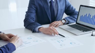 Bir dizüstü bilgisayarda finansal verileri tartışan çok sayıda iş arkadaşından oluşan bir ekip, görevdeki grafikleri ve pazar eğilimlerini analiz ediyor. İş adamları ve finans kavramı.