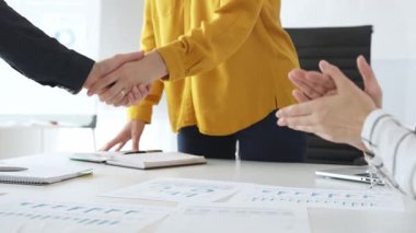 Profesyonel iş arkadaşları anlaşmayı mühürlüyor, ortaklığı alkışlarla, mali evraklarla ve başarılı iş görüşmelerini çevreleyen dijital cihazlarla kutluyorlar.