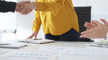 Profesyonel iş adamları el sıkışıyor, çağdaş ofis çalışma alanındaki toplantı masasının başında dururken ortaklık anlaşmasını onaylıyorlar. İş tokalaşması.