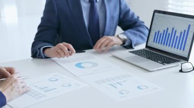 Finansal analizleri inceleyen profesyonel ekip, işbirlikçi toplantı sırasında basılı raporları ve dijital çizelgeleri inceliyor. İş adamları ve finans kavramı