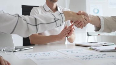 İş adamları iş yeri belgelerinin üzerinden el sıkışıyor, işbirliği ruhunu sembolize ediyor ve işyerindeki başarıyı paylaşıyorlar. El sıkışma kavramı.