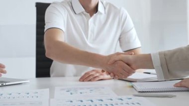 İş adamı, iş yeri belgeleri üzerinde kadın partnerle tokalaşıyor, işbirlikçi ruhu simgeliyor ve işyerindeki başarıyı paylaşıyor. İş tokalaşma kavramı.