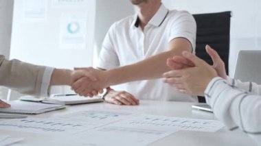 İş adamı, iş yeri belgeleri üzerinde kadın partnerle tokalaşıyor, işbirlikçi ruhu simgeliyor ve işyerindeki başarıyı paylaşıyor. İş tokalaşma kavramı.