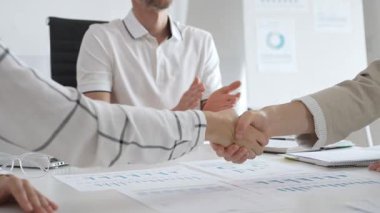 İş adamları iş yeri belgelerinin üzerinden el sıkışıyor, işbirliği ruhunu sembolize ediyor ve işyerindeki başarıyı paylaşıyorlar. El sıkışma kavramı.