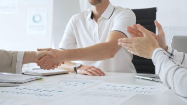 İş adamı, iş yeri belgeleri üzerinde kadın partnerle tokalaşıyor, işbirlikçi ruhu simgeliyor ve işyerindeki başarıyı paylaşıyor. İş tokalaşma kavramı.