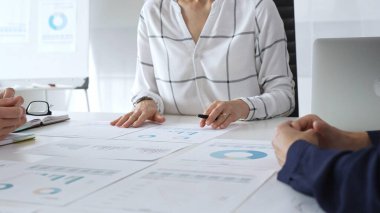 Bir iş toplantısı sırasında finansal belge ve çizelgeleri analiz eden bir grup profesyonel. Takım üyeleri veri analizi, strateji planlaması ve kurumsal büyüme hedeflerinde işbirliği yaparlar.