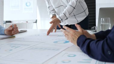 Toplantı sırasında finansal belgeler, çizelgeler ve grafikler ile modern ofiste takım işbirliği, strateji, planlama ve analiz tartışan profesyoneller