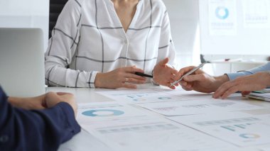 Bir iş toplantısı sırasında finansal belge ve çizelgeleri analiz eden bir grup profesyonel. Takım üyeleri veri analizi, strateji planlaması ve kurumsal büyüme hedeflerinde işbirliği yaparlar.