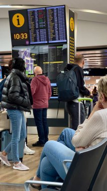 Londra, İngiltere: 26 Mart 2024 - Gezginler uçuş bilgilerini güncellemek için büyük dijital ekran panosunu kontrol ediyorlar