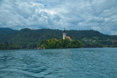 Slovenya 'da Bled Gölü, Kan Kanı Kilisesi ve Julian Alpleri' nin panoramik manzarası yemyeşil yemyeşil ormanlarla dolu